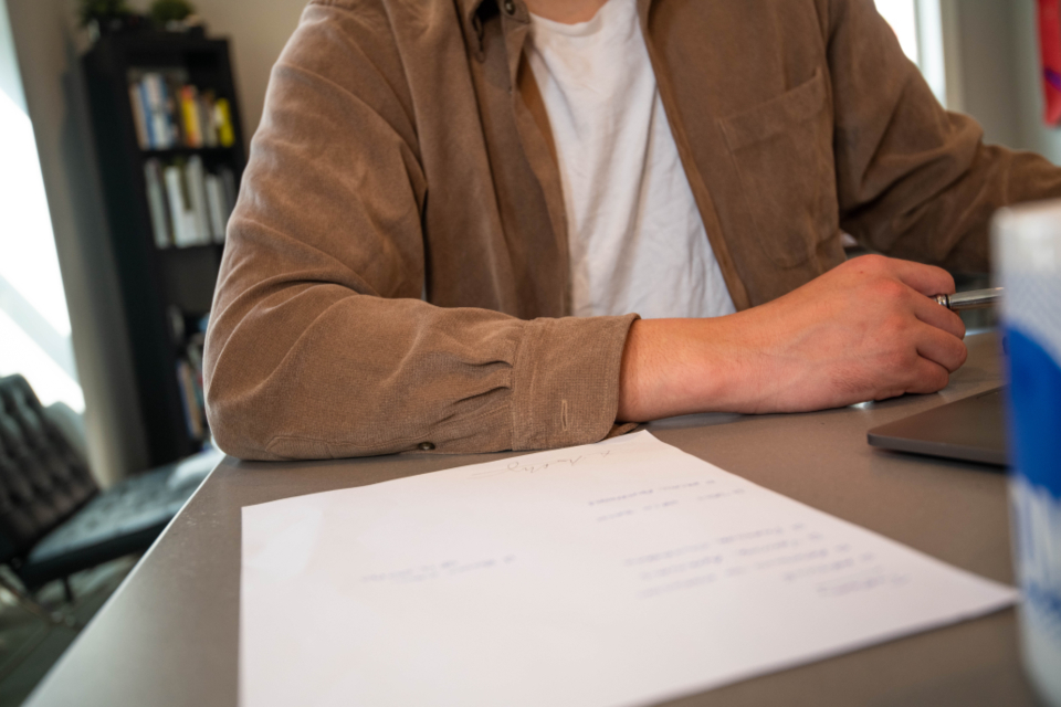 Person bearbeitet Unterlagen am Schreibtisch zum Thema Bürokratieabbau