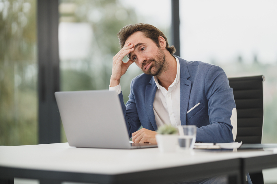 Erschöpfter Manager stützt den Kopf am Schreibtisch zum Thema Resilienz