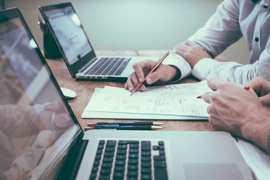 Laptop und Unterlagen auf dem Schreibtisch zur Arbeitszeiterfassung im Kleinbetrieb