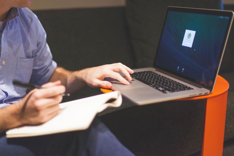 Hände an Laptop und Notizbuch beim Schreiben von Texten zum Thema Content-Marketing