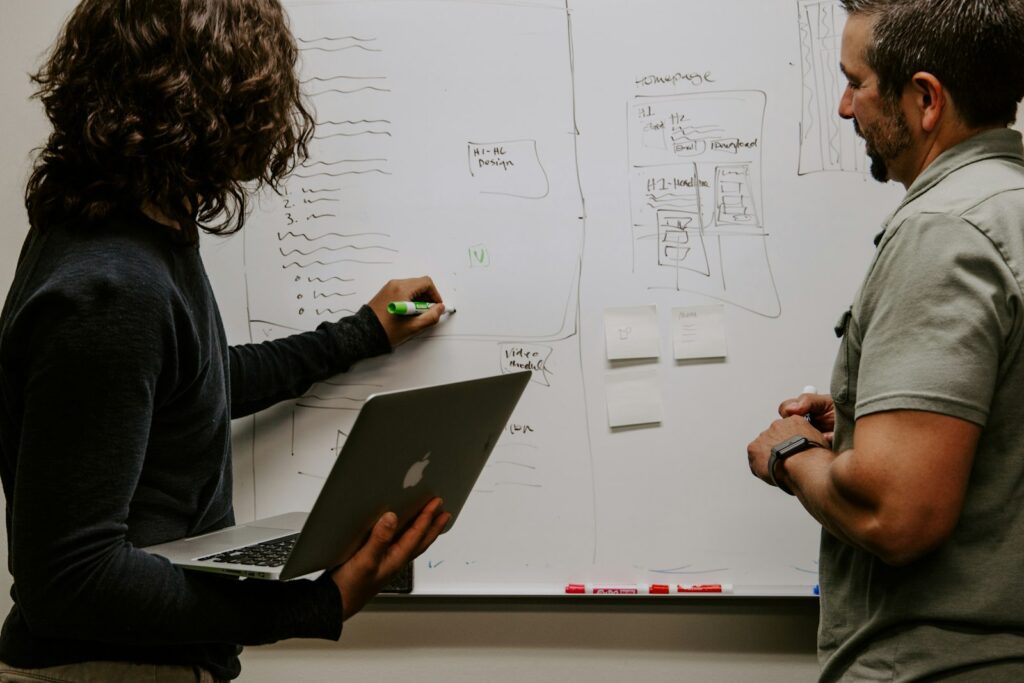 Führungskraft erklärt einer Kollegin am Whiteboard eine Aufgabe – Delegieren im Team