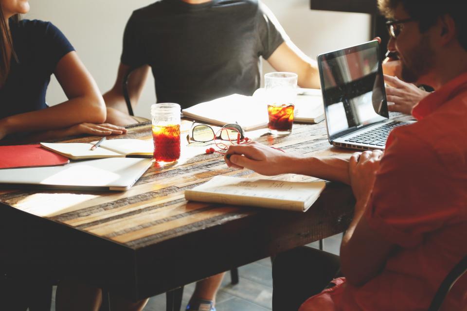Team arbeitet gemeinsam an einem Tisch mit Laptops und Notizen zum Thema Delegieren