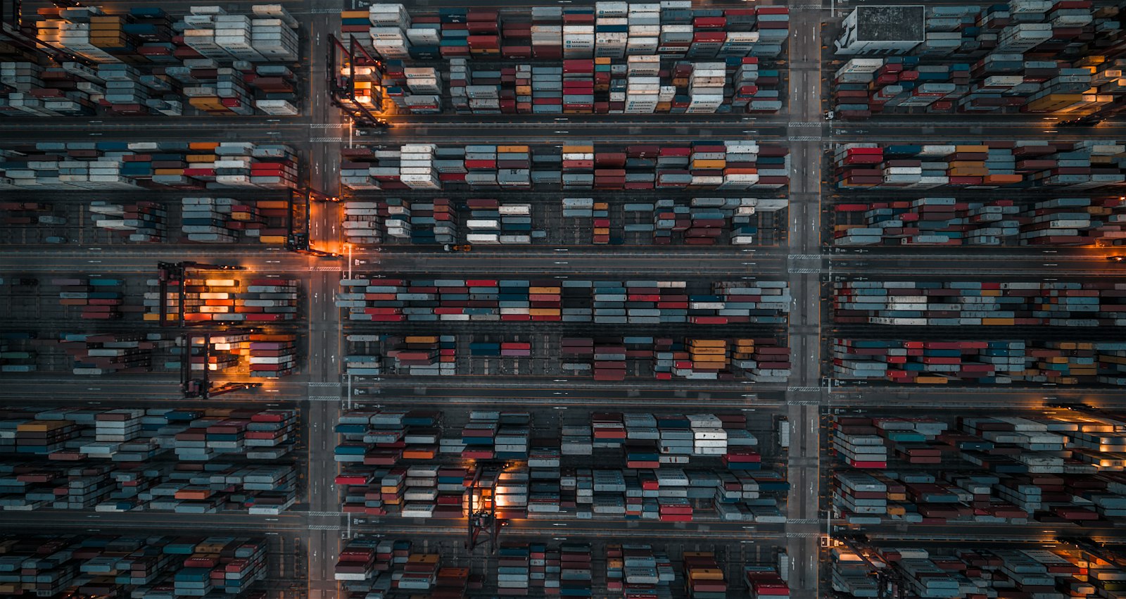 Containerterminal mit Beleuchtung bei Nacht aus der Vogelperspektive