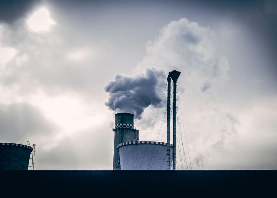 Rauchender Industrieschornstein vor bewölktem Himmel