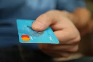 Hand reicht eine Bankkarte über den Tisch zum Thema Kontokorrentkredit