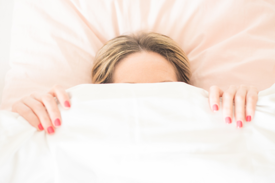 Kranke Frau liegt im Bett unter der Decke zum Thema Krankmeldung nach Kündigung