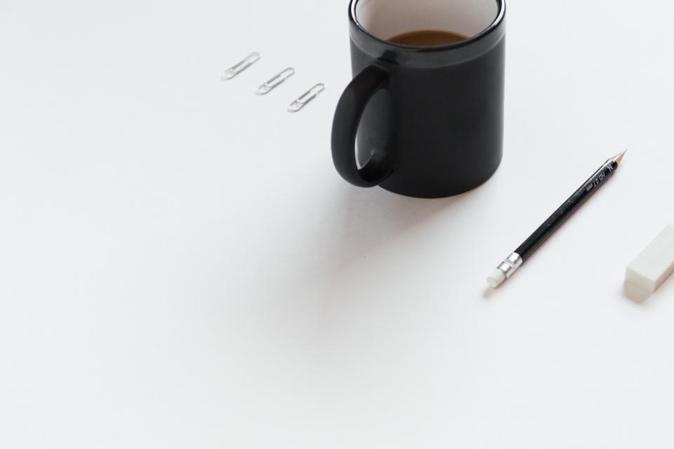 Kaffeetasse und Stift auf einem leeren Schreibtisch