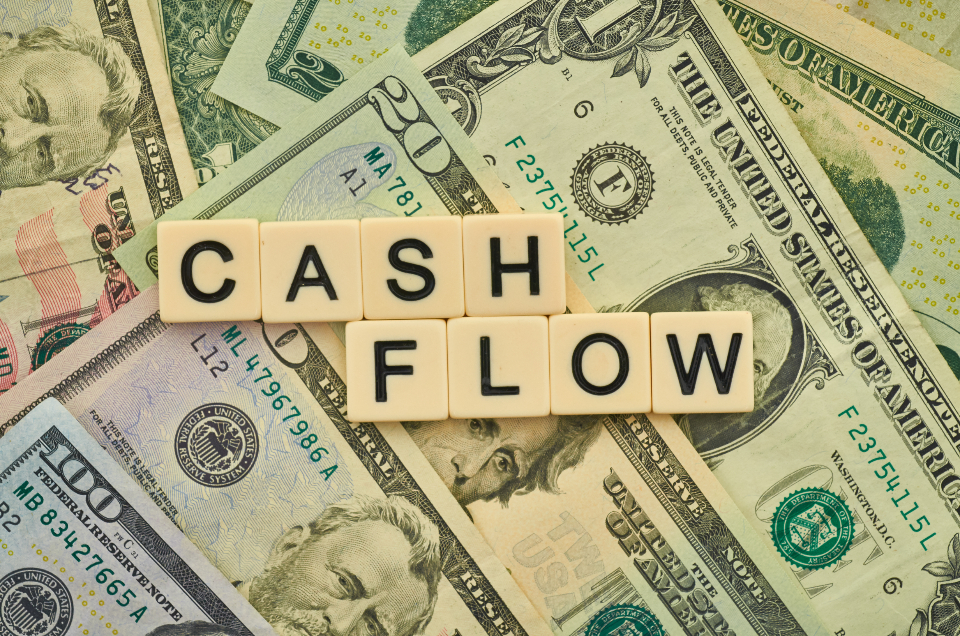 Holzbuchstaben mit dem Wort Cash Flow auf Geldscheinen zum Thema Liquiditätsplanung