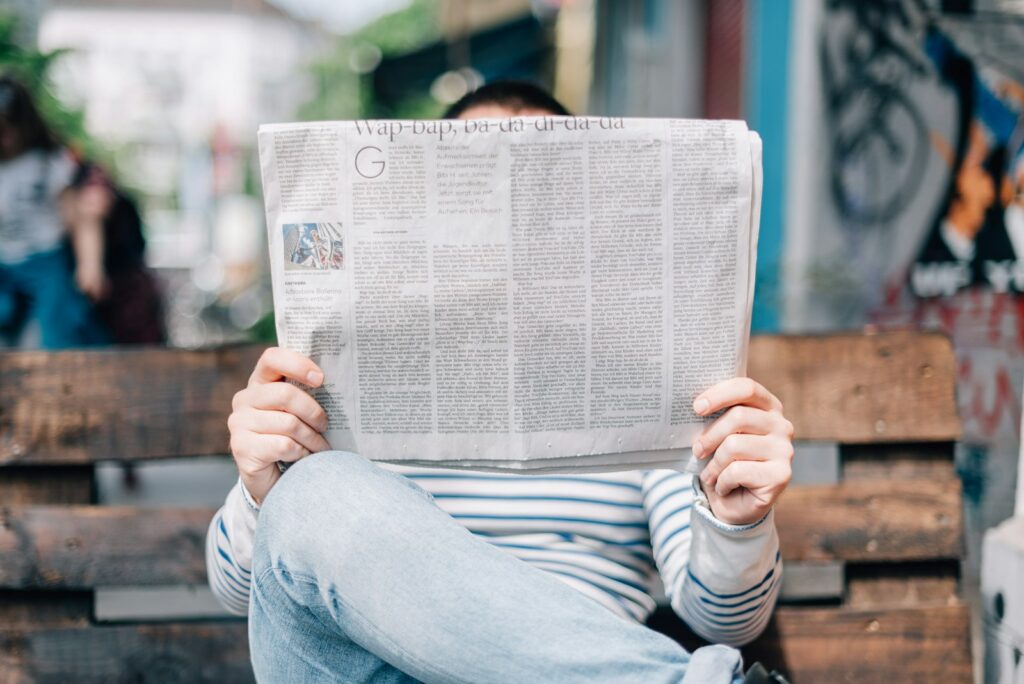 Person liest Zeitung mit Wirtschaftsnachrichten über eine Rezession
