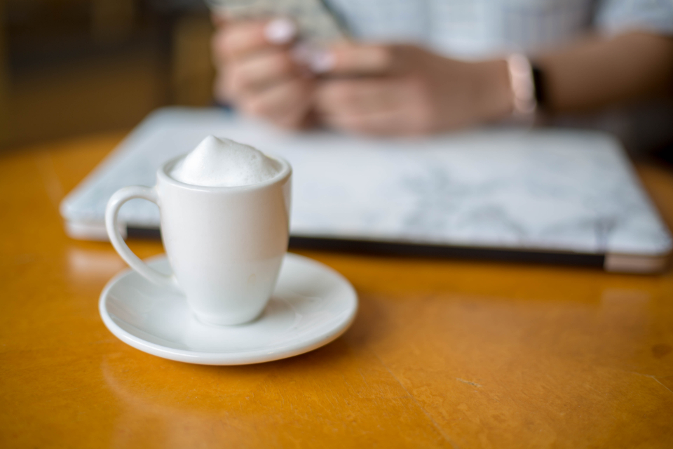 Kaffeetasse neben Laptop am Arbeitsplatz zum Thema Stundensatz berechnen